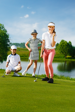 Kids playing golf by putter on greenの写真素材