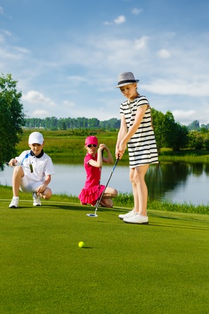 Kids playing golf by putter on greenの写真素材