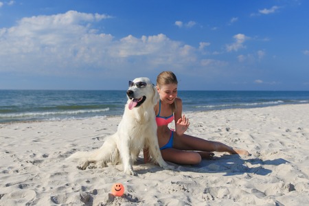 Beautiful girl playing with a playful Golden retriever on the sea shore. Outdoor portrait. series