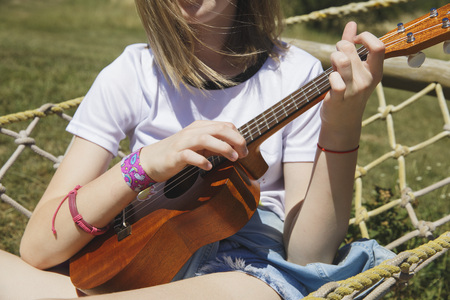 Beautiful girl playing ukulele - hawaiian guitar in hammockの写真素材