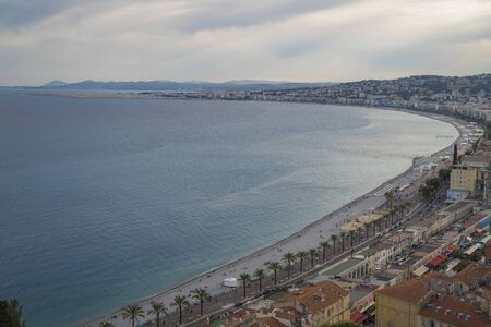 Luxury resort of French riviera. Beautiful view at city of Nice in France. Mediterranean sea, public beach, famous quay, palms and houses of Nice.の写真素材