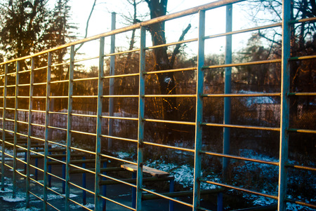 The sport ladders on the playground covered with warm yellow light of winter afternoon twilight.