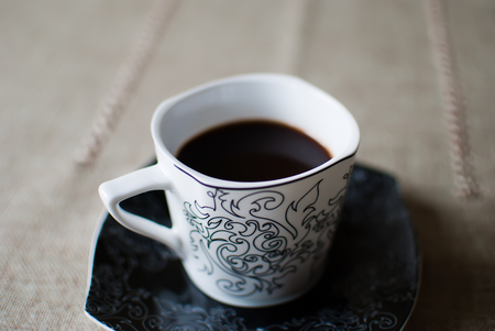 White cup of coffee on a black saucerの写真素材