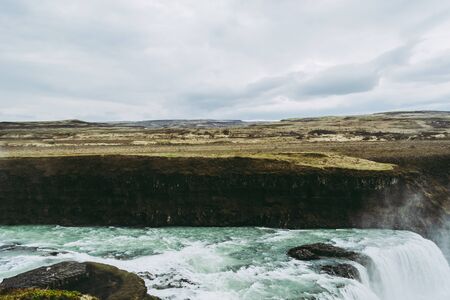 Horizontal view of Gullfoss waterfall in Southwest Iceland. Blue and green water with pale white splashes flying over it. Icelandic landscapes.の写真素材