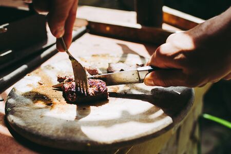 Homemade burrito preparation. Man chef cutting small pieces of beef well done stakes.