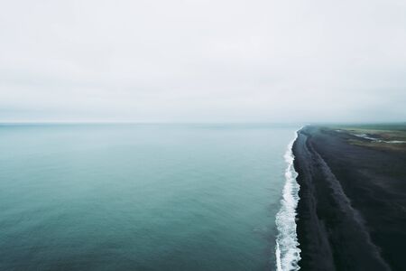 Atmospheric view from Dyrholaey lightouse cliff over the black sand beach. Icelandic landscapesの写真素材