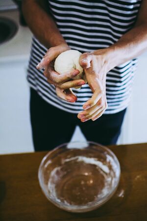 Man kneading pizza dough over the transparent plateの写真素材
