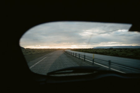 Sunset caught in the rear window of the car during the road trip on a highway in Iceland. Film photographyの写真素材
