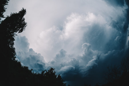 Dramatic dark blue sky before the storm. Wide angle fisheye cloudscape in the summer afternoon in Lviv, Ukraine. Bright light coming from behind the clouds.の写真素材