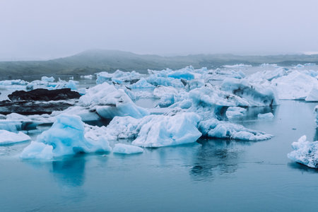 Bright white glaciers covered with dense fog in the blue waters of Jokulsalron glacial lake in Icelandの写真素材