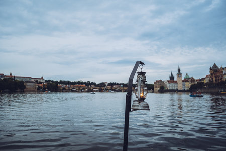 Old vintage lantern hanging over the waters of Vltava river in the beautiful city of Prague, one of...