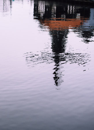 Blurry reflection of a famous de Adriaan watermill in the Spaarne river. Tiny waves on a windy blue...