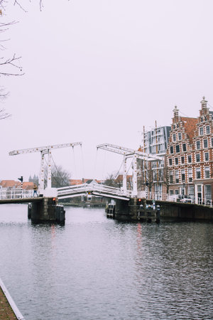 White drawbridge over the water of the river in Haarlem, Netherlands. Typical Holland cityscape. Cold cloudy weather.の写真素材