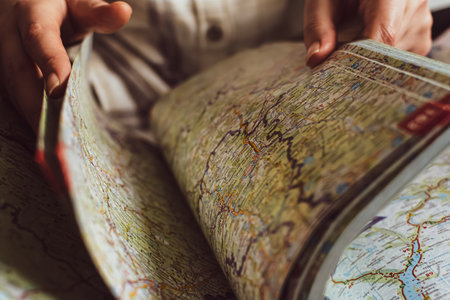 Hands turning the pages of a roadmap, searching for a new travel destination