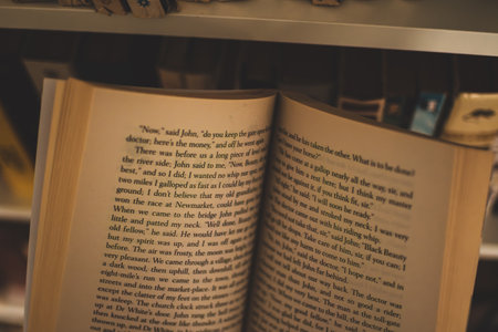 Open book against a bookshelf. A look from the reader's perspective. Old classic novel.の写真素材