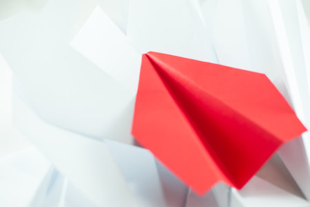Red paper plane among white ones on a white background, isolated. Concept (idea) of airlines, freedom, leadership, success, and individualism.の写真素材