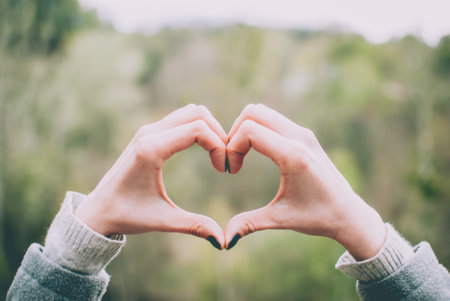 Tender girl's pale hands forming a heart shape gesture. Concept (idea) of love, friendship, romance, passion.の写真素材