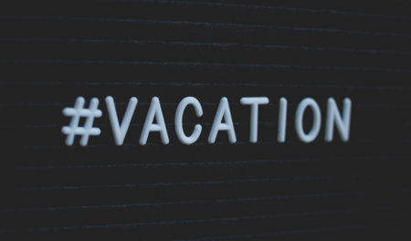 Hashtag word #vacation written on the letter board. White letters on the black background.の写真素材