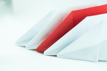 Red paper plane among white ones on a white background, isolated. Concept (idea) of airlines, freedom, leadership, success, and individualism.の写真素材