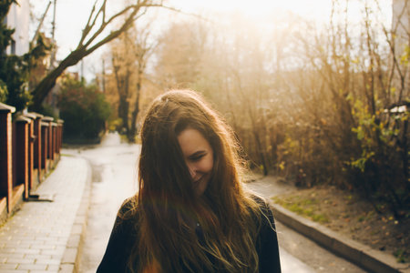 Joyful smiling girl with her beautiful long hair tousled on a sunny windy day. Sunny autumn street...