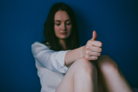 Sad handsome caucasian brunette demonstrating a thumbs up gesture. Deep shadows and high contrast....