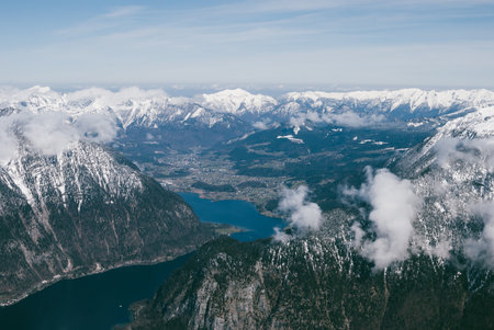 Spectacular view of snowy mountain peaks in Austrian Alps. Clouds flying above evergreen forests. Beautiful dreamy landscape.の写真素材