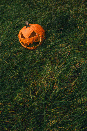 Jack-o'- lantern lying on green October grass on Halloween
