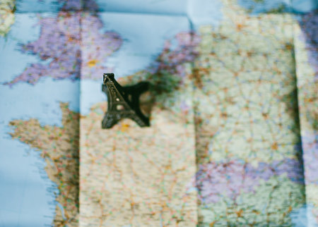 Traveler's road map. Eiffel tower souvenir standing on the map near Paris, France, and casting deep...