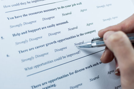 Respondent holding a pan in a hand and answeing questions in employee survey. Questions relating to managerial practices, corporate culture, career growth, and professional relationships. Close-upの写真素材