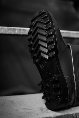 Emergency services work boots. Heavy  rubber shoes used in cases of natural disasters, ecological catastrophes, armed conflicts, fires. Boots laying on the stairs in the storage.の写真素材