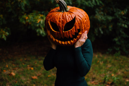 A woman with a pumpkin head on halloween in the forest. Halloween costume idea for a womanの写真素材