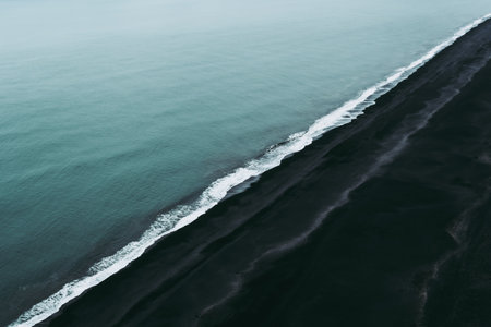Turquoise water, white foam, and black sand. Magical and calm atmosphere in Vik, Iceland.の写真素材