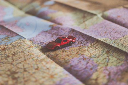 Closeup of a traveler's road map in vintage retro colors. Small red car crossing the map.の写真素材