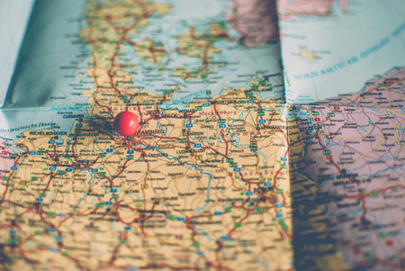 Closeup of a traveler's road map in vintage retro colors. Countries and cities of Western Europe on the map. Red push pin marking Hamburg, Germanyの写真素材