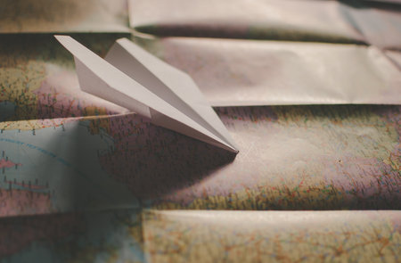 Closeup of a traveler's road map in vintage retro colors. White paper plane flying over Europeの写真素材