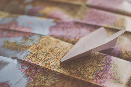 Closeup of a traveler's road map in vintage retro colors. White paper plane flying over Europeの写真素材