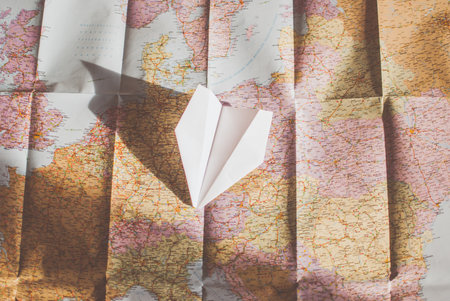Closeup of a traveler's road map in vintage retro colors. White paper plane flying over Europeの写真素材