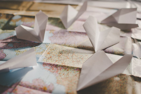 Closeup of a traveler's colorful road map in vintage retro colors. Few white paper planes flying over Europe in different directionsの写真素材