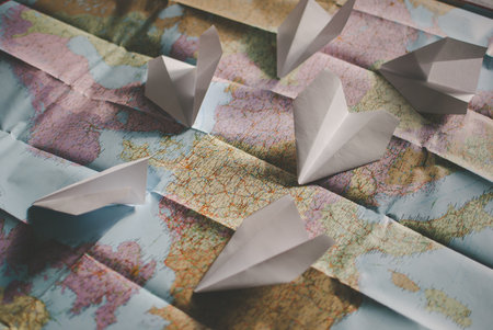 Closeup of a traveler's colorful road map in vintage retro colors. Few white paper planes flying over Europe in different directionsの写真素材
