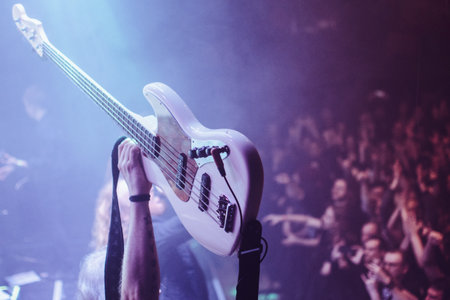 Energetic concert scene with a raised bass guitar over a cheering crowd, symbolizing passion, unity, and raw power of live music performance.の写真素材