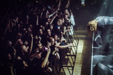 Metal vocalist performing with passion on stage during a club show, with colorful dramatic lighting