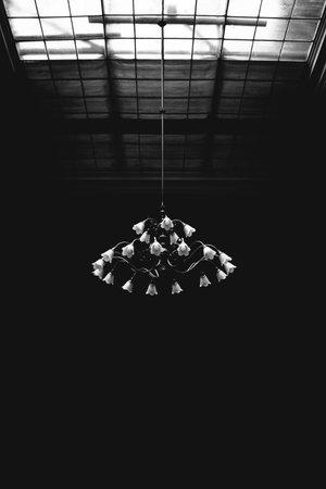 Minimalist black and white photograph of a vintage chandelier hanging under a skylight, with an elegant, moody, and timeless interior atmosphere.の写真素材