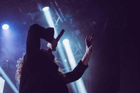 Metal vocalist performing passionately on stage during a club show, with colorful dramatic lightingの写真素材