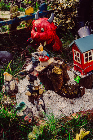 Whimsical garden scene in Nikiszowiec, Katowice, Poland, featuring small animal figurines and a tiny red house on white gravel.の写真素材