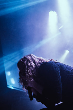 Metal vocalist performing passionately on stage during a club show, with colorful dramatic lightingの写真素材