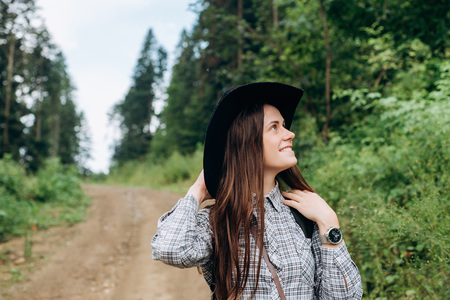 Happy woman traveler, looking at the wonderful forest, the concept of travelers, the place for the text, the atmospheric epic momentの写真素材