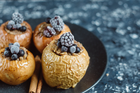 Fruit dessert baked apples stuffed with blackberry, blueberries, cinnamon, nuts, honey. Autumn or winter dessert.の写真素材