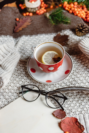 Flat lay-out of a leaf with a tartan textured sweater on a wooden background with a cup of tea. Autumn or Winter concept.の写真素材