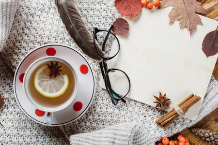 Flat lay-out of a leaf with a tartan textured sweater on a wooden background with a cup of tea. Autumn or Winter concept.の写真素材