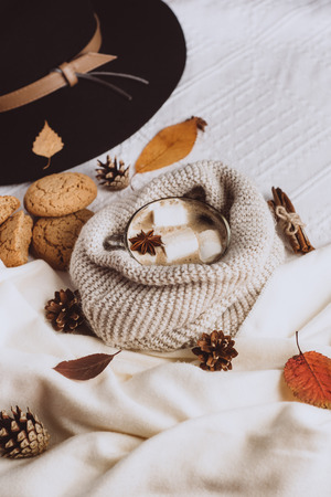 Autumn and Winter composition. Hot coffee with marshmallows, scarf, cookies, hat, bumps and autumn leaves. Flat lay, top viewの写真素材